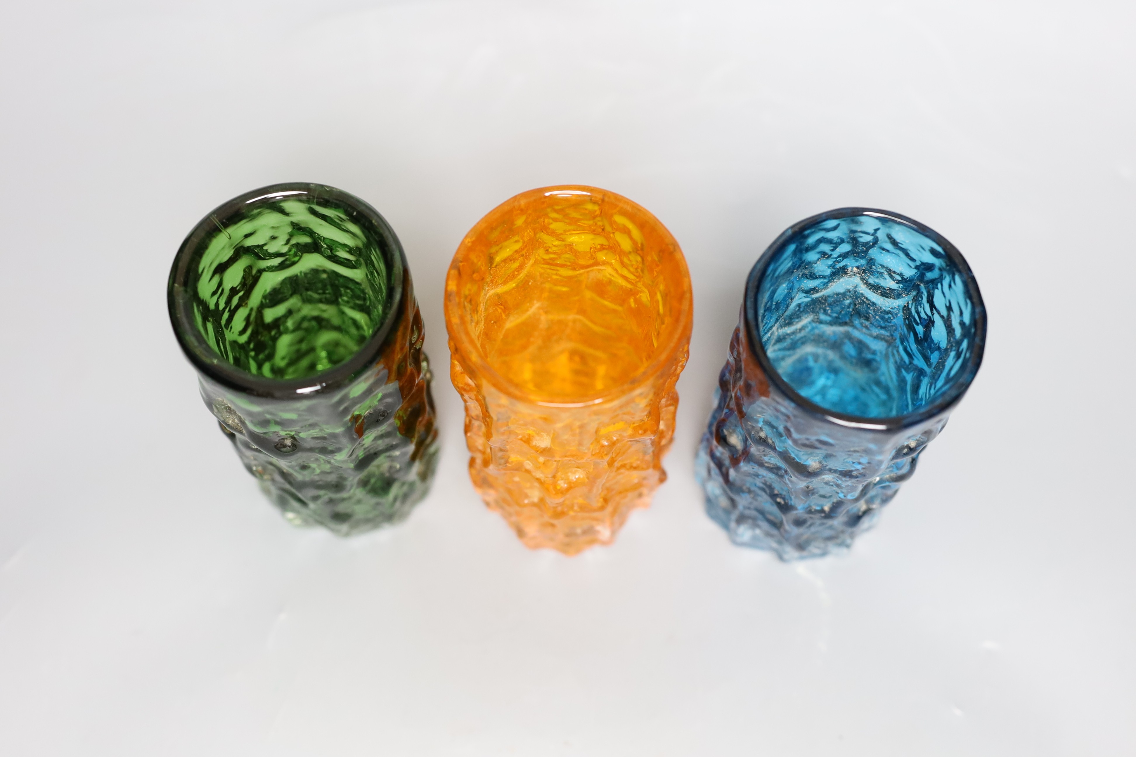Three Whitefriars 'bark' cylinder vases, model 9689 designed by Geoffrey Baxter, kingfisher blue, tangerine and green glass, each 15cm high.